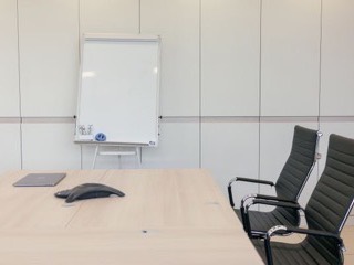 A bright office room with a whiteboard and a meeting table ready